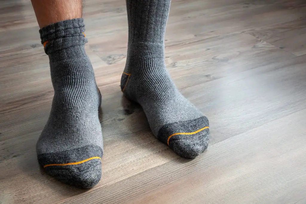 male feet in grey socks on a wooden floor