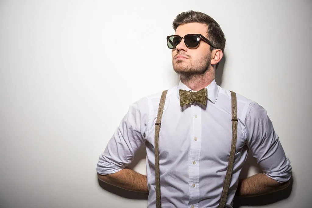 young trendy man with black glasses, suspenders and bow-tie