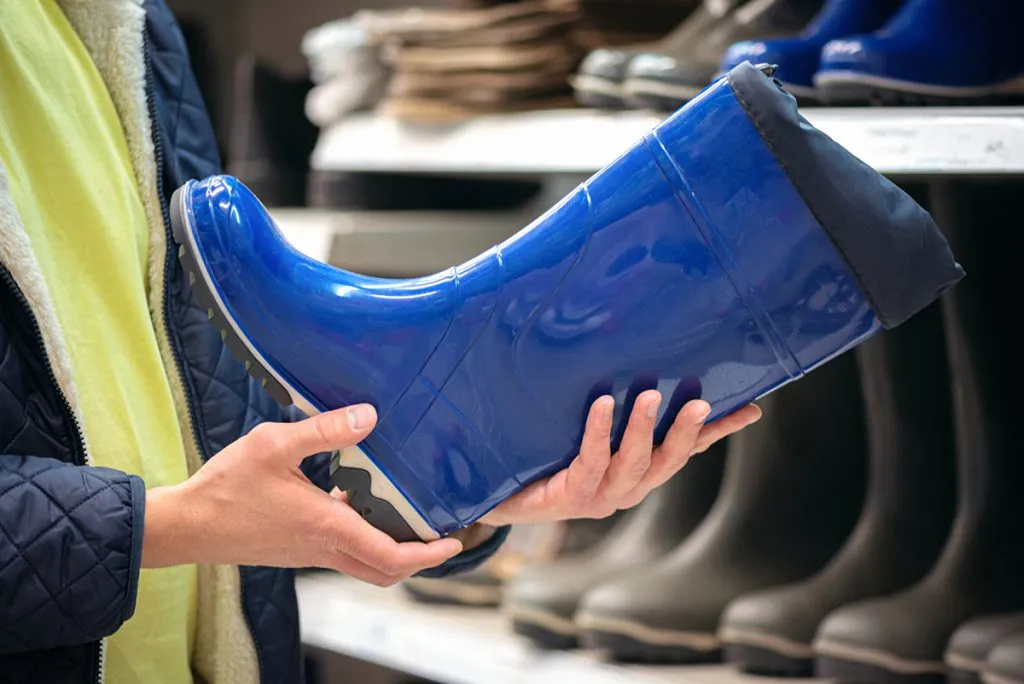 man buying a new rubber boots in a store