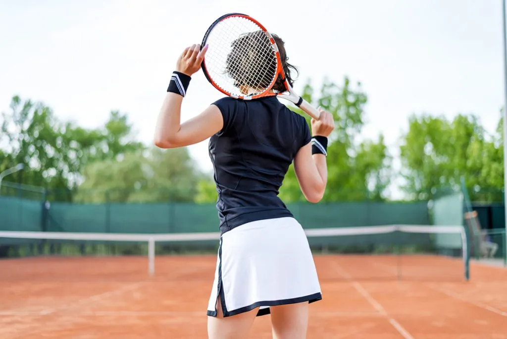 young girl on an open tennis court playing tennis
