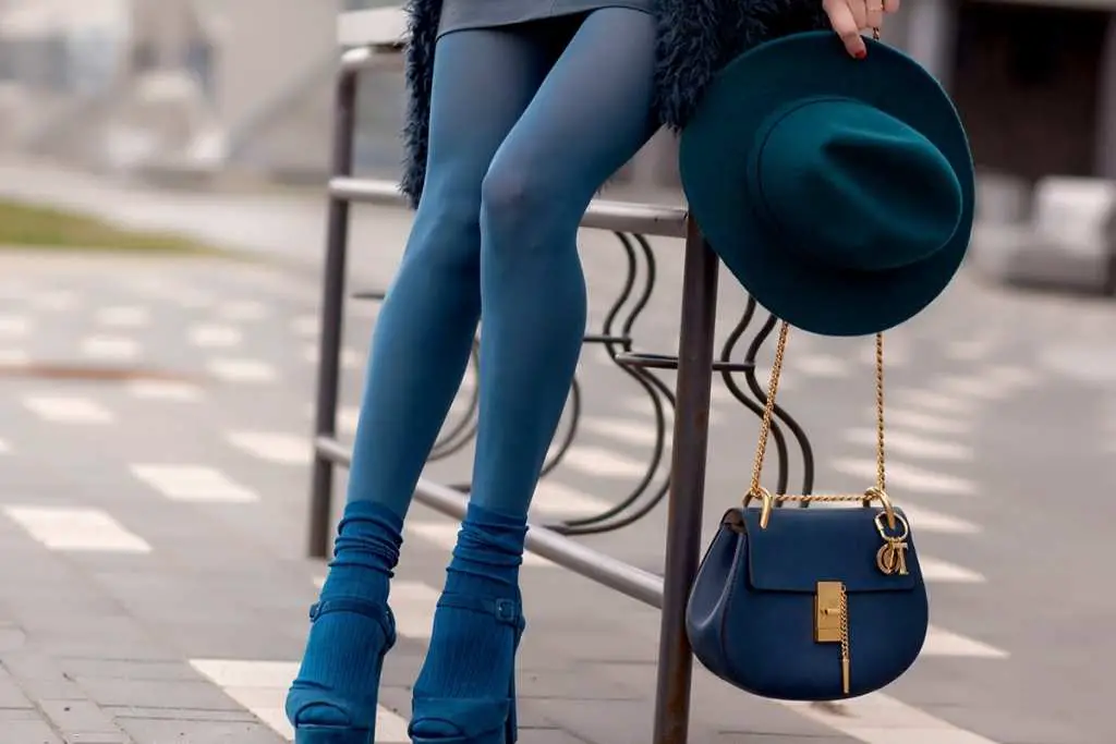 girl in leggings and a hat with a handbag