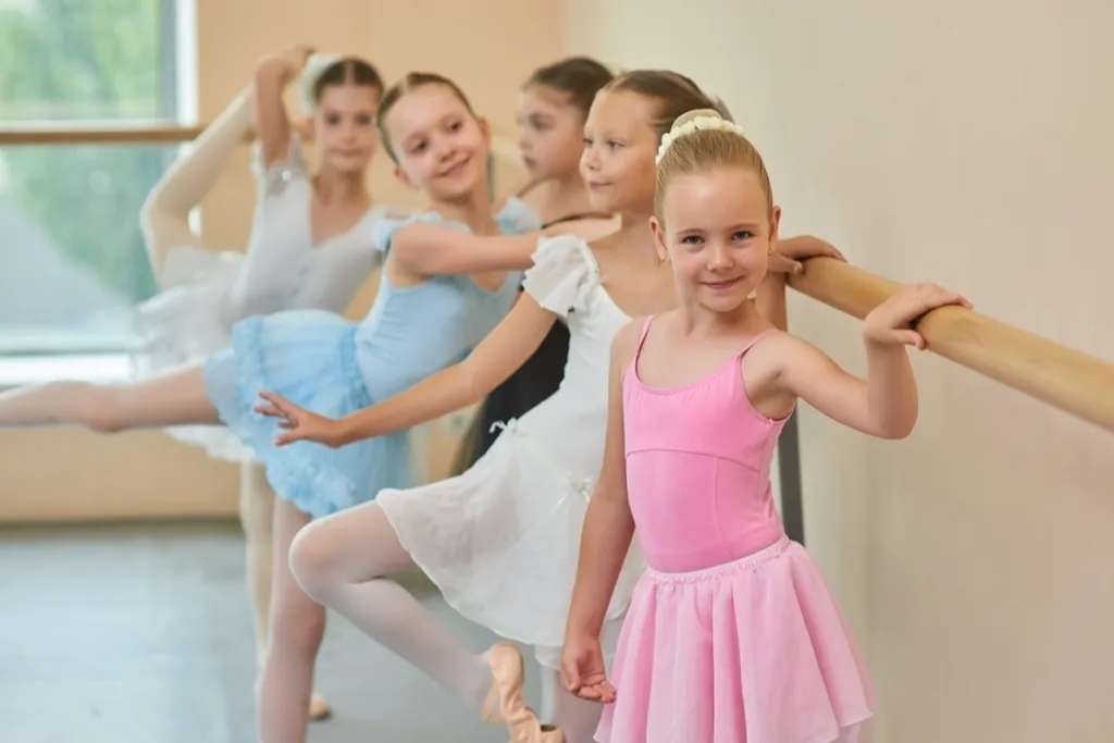 ittle ballet girl standing at ballet barre in studio