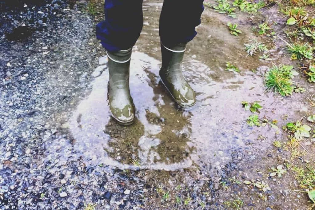 man in boots in a small muddy puddle