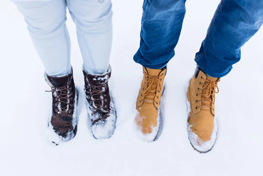 couple's boots and legs wearing pants stood in the snow