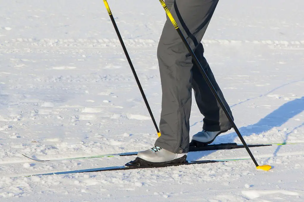 man wearing snow pants and ski boots skiing in the winter