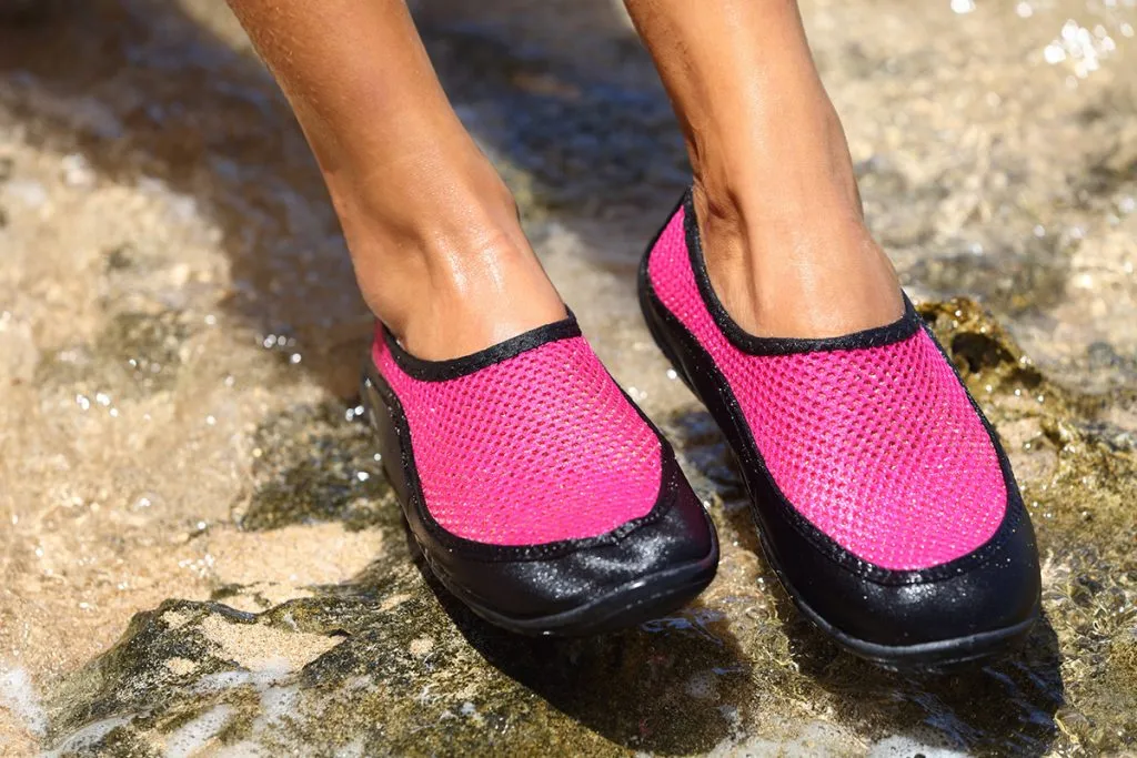 swim shoes in pink neoprene on rocks in water on the beach