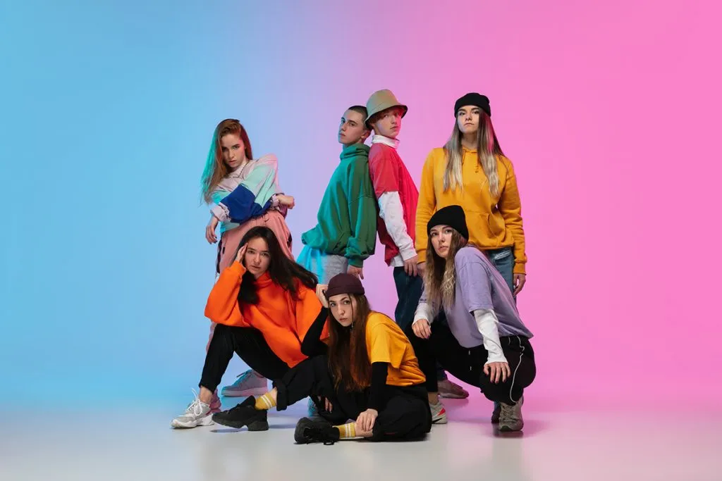 hip-hop dancers dressed stylishly perform on a neon-lit gradient studio