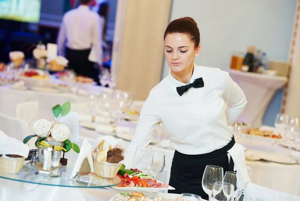 woman with food on dishes servicing in restaurant during catering the event
