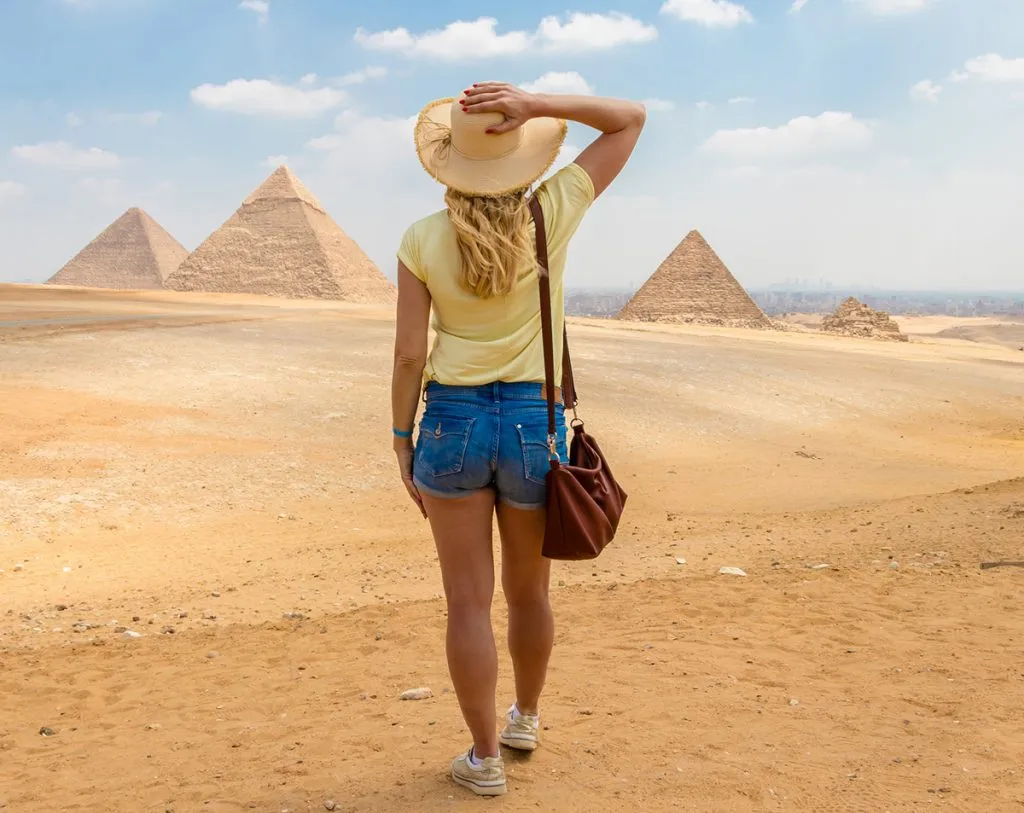  woman wearing shorts watches the Great Pyramids of Giza in Egypt