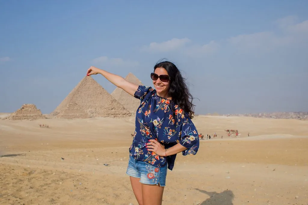 woman in shorts against a backdrop of Egyptian pyramids 