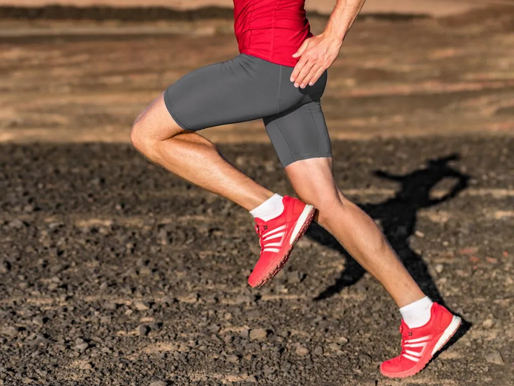 man in compression shorts is running through landscape terrain 