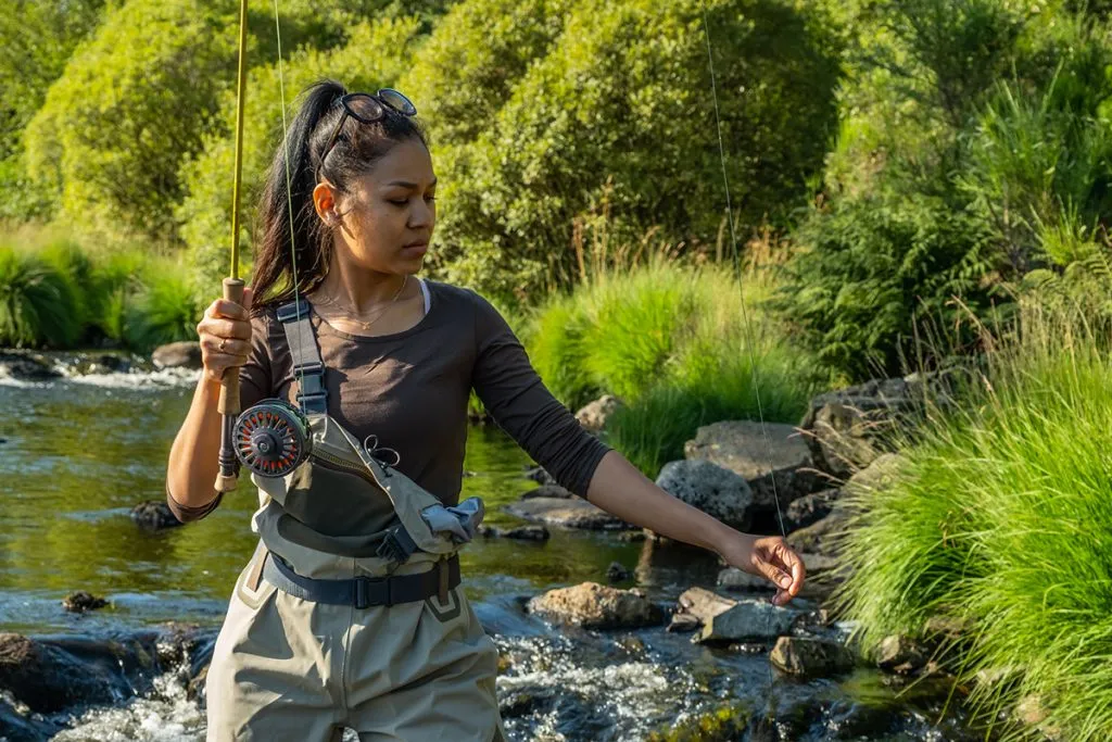 asian female standing fly fishing in a riffle on a river