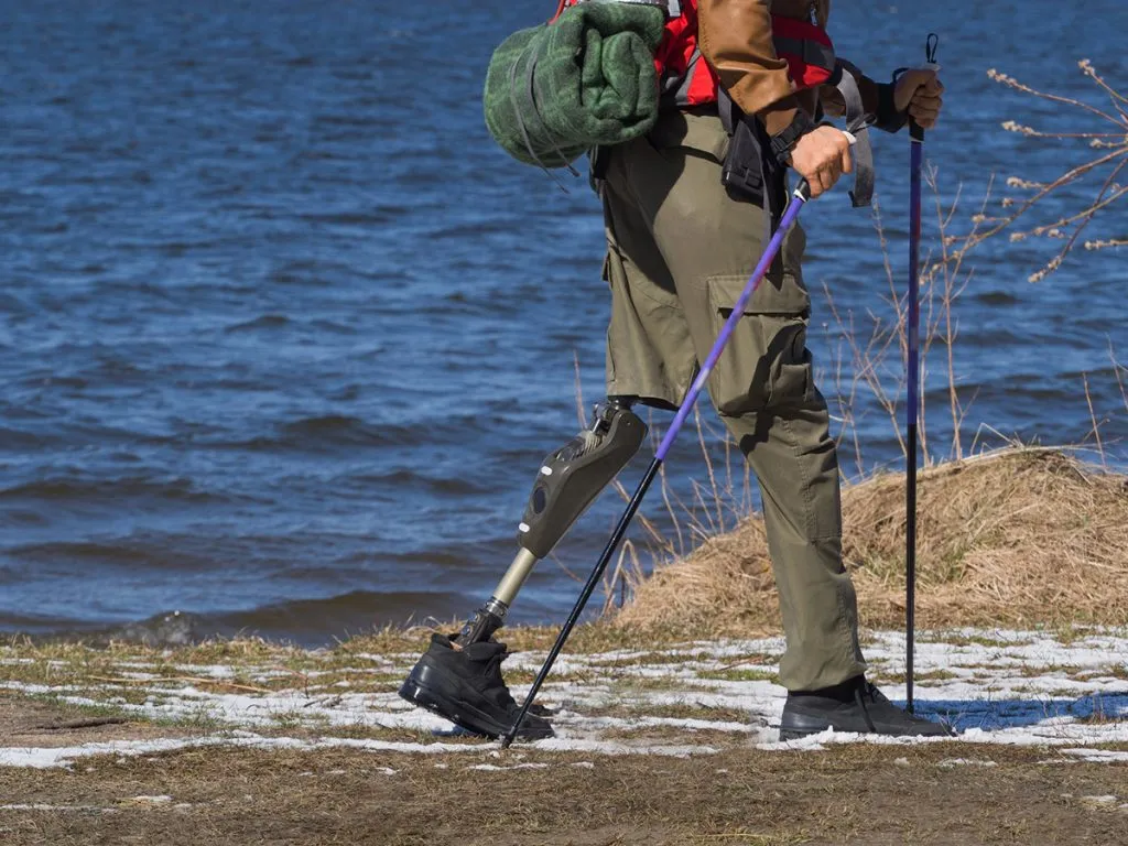 man with prosthesis of a leg walking by the river