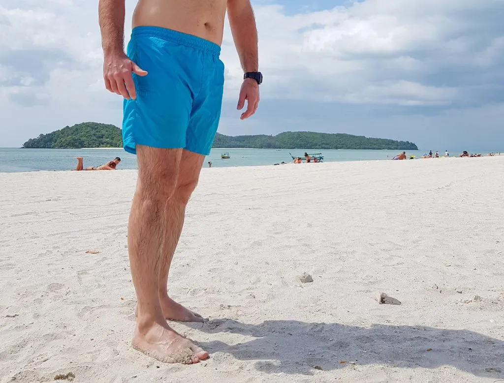 on a tropical beach, a man wears swimming trunks