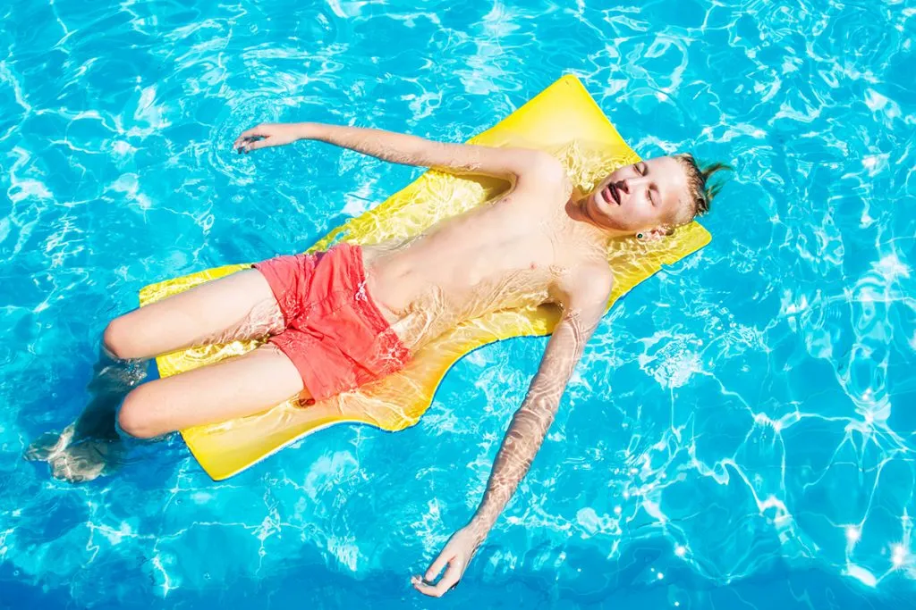 teenager in red swimming trunks relaxes in the pool