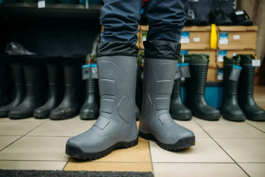 fisherman tries on rubber boots in fishing shop