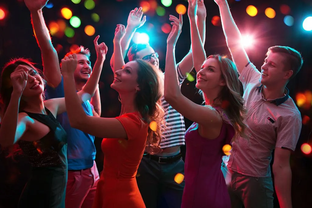 group of happy young people having fun dancing at party