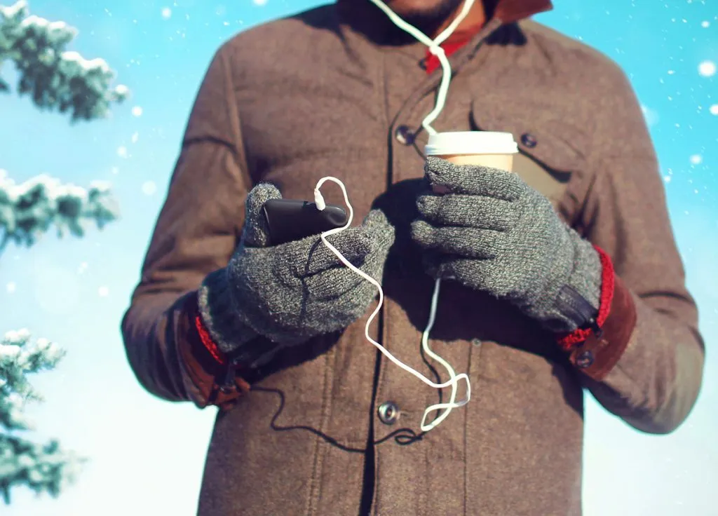 man listens to music on a smartphone drinks coffee