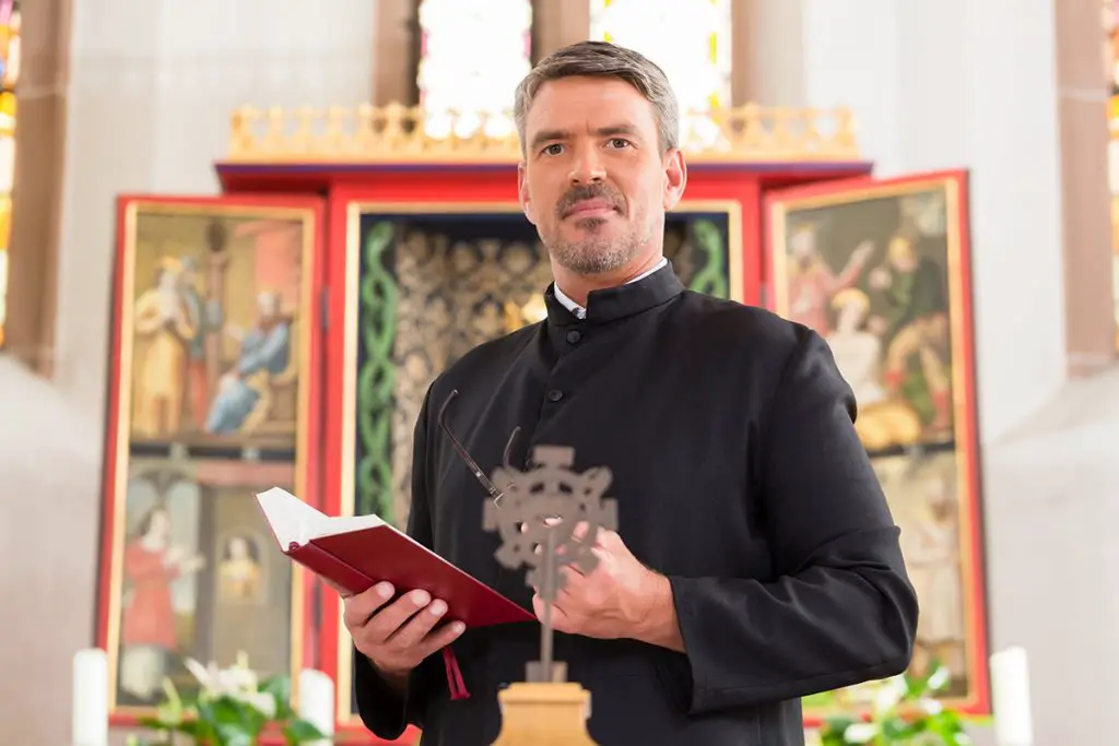priest in church with bible in front of altar