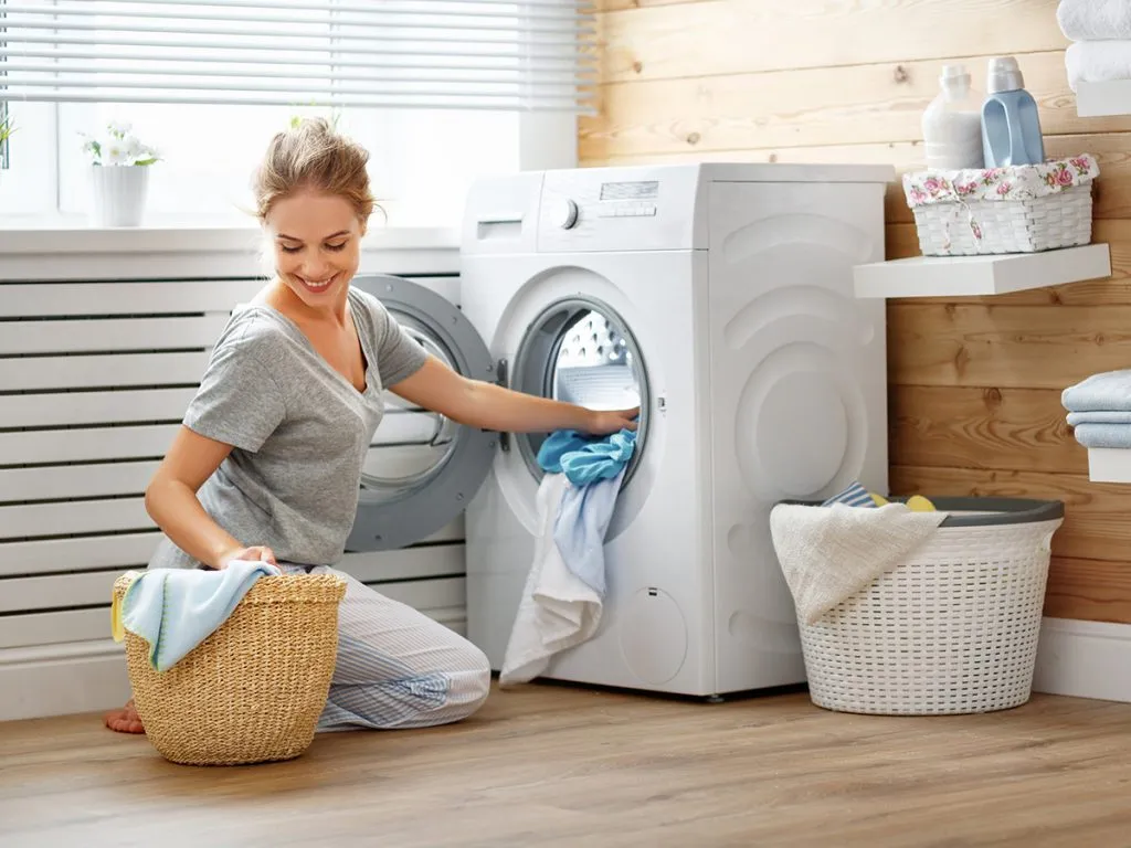 happy housewife woman in laundry room with washing machine