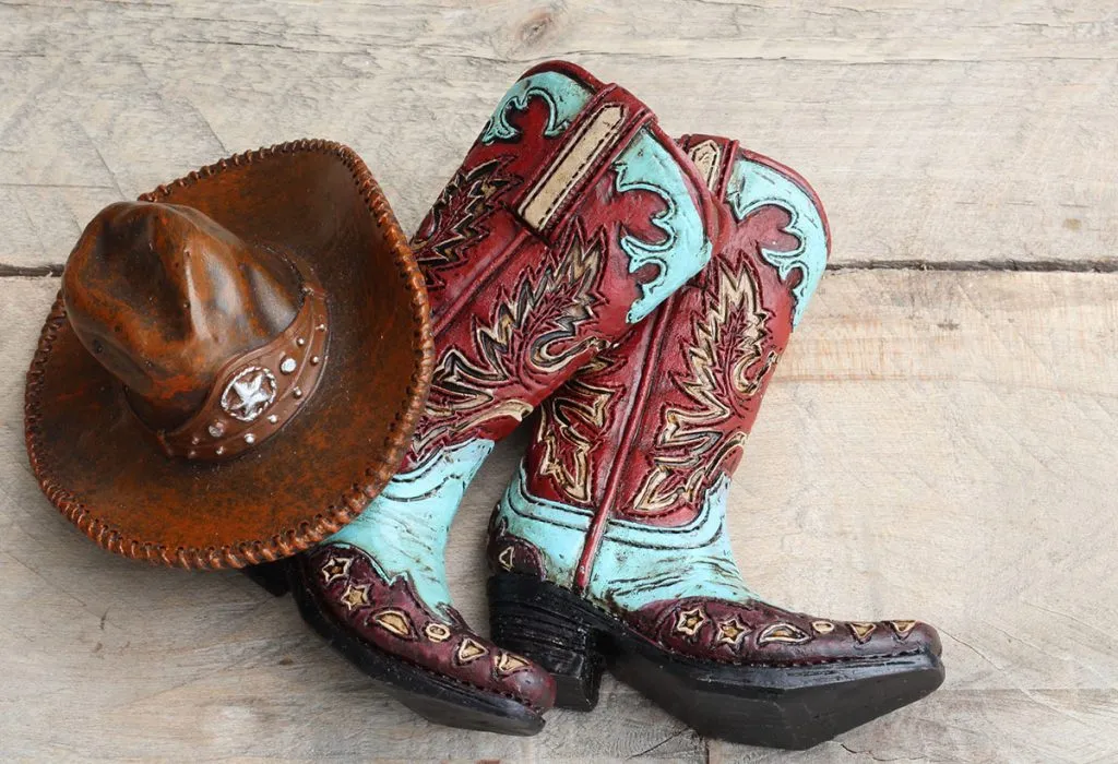 pair of cowboy boots with a cowboy hat close up laying on a wood