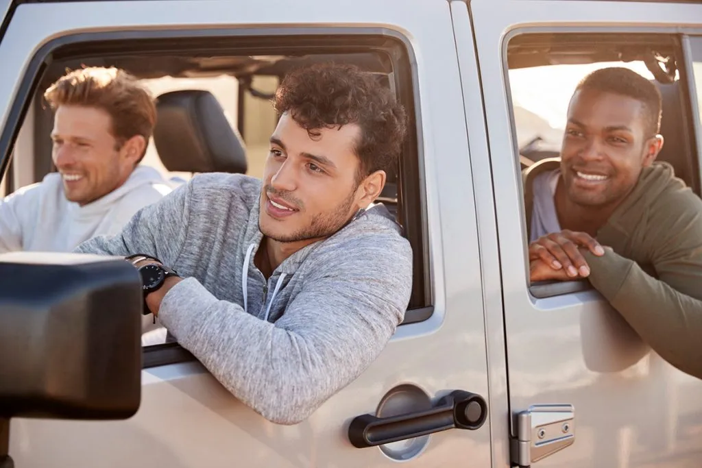 three young adult male friends are going on vacation in a car