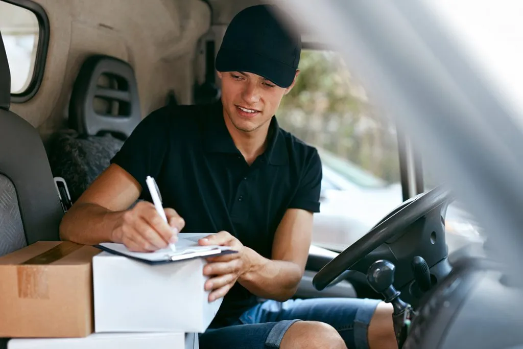 In a car, a man wearing shorts delivers packaging with bosex