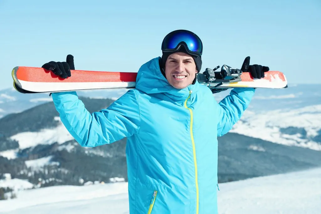 man wearing hoodie with ski equipment in mountains