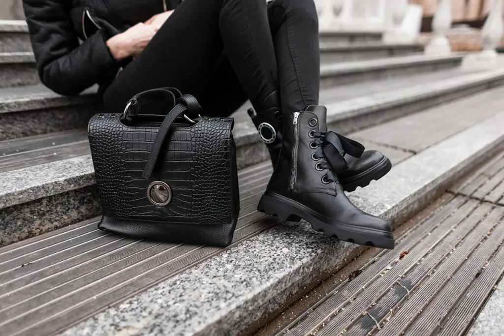 female legs in jeans in boots with a leather fashion handbag