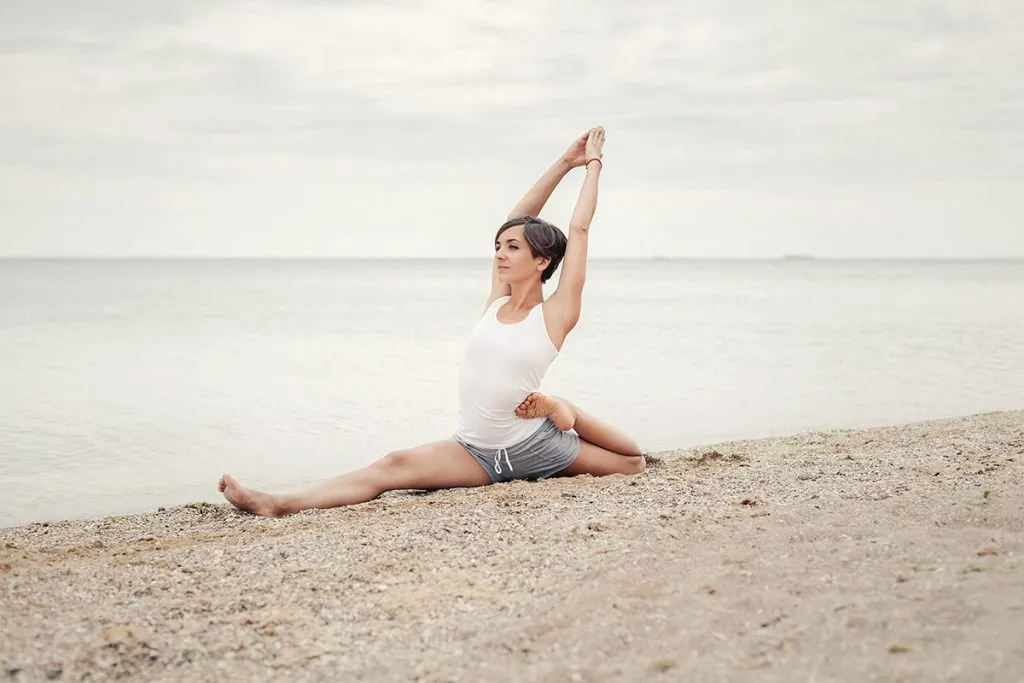 a girl with a short hairstyle dressed in shorts and a white jersey makes a twine on the background of the sea and the beach. Playing sports in nature