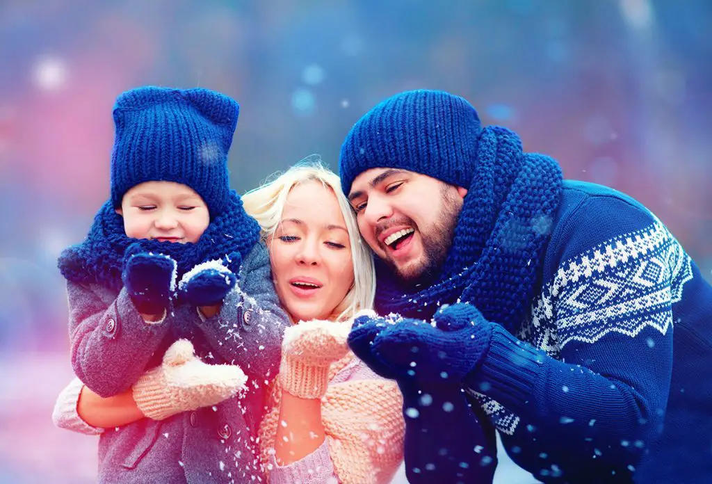 happy family blowing winter snow