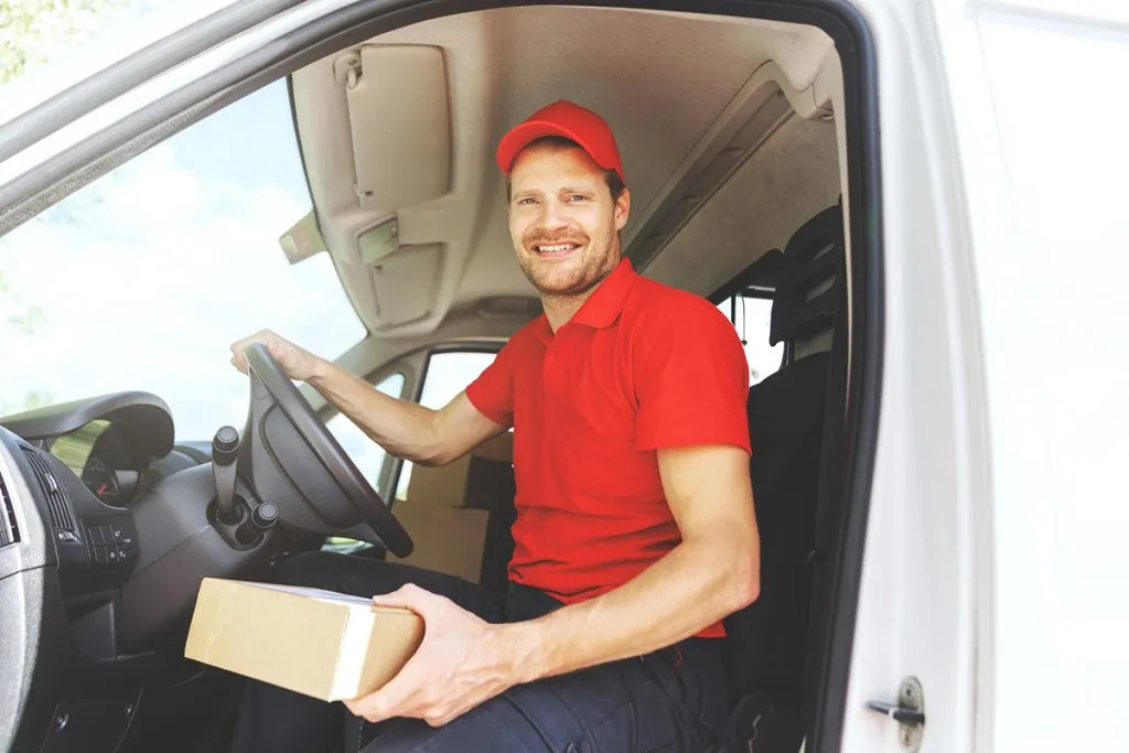 driver in red uniform sitting in van with box in hand