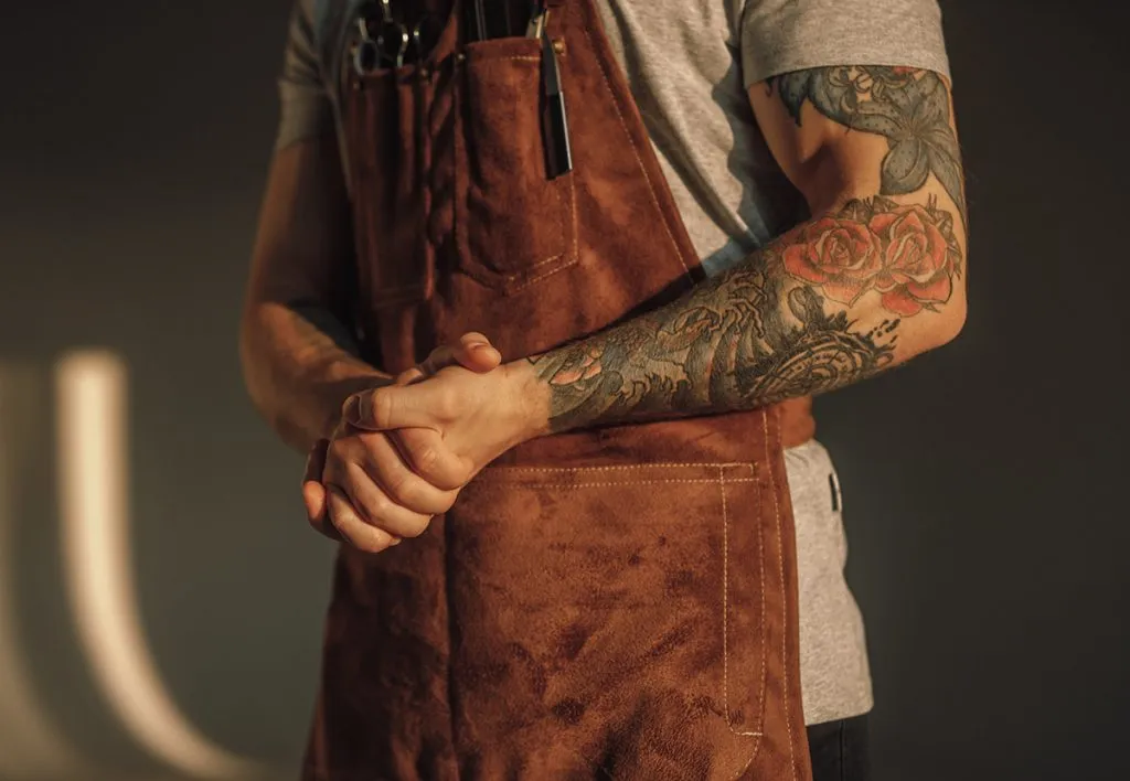 man in brown apron clasping hands