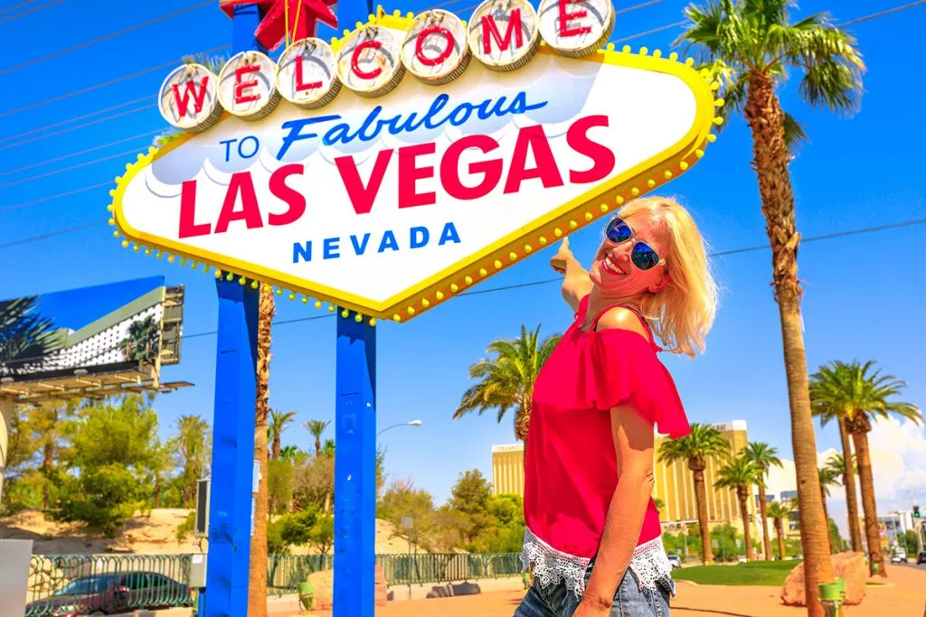 happy tourist woman pointing welcome to fabulous las vegas nevada sign