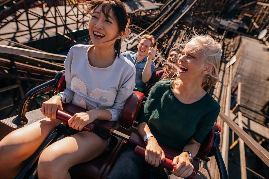 smiling young people riding a roller coaster
