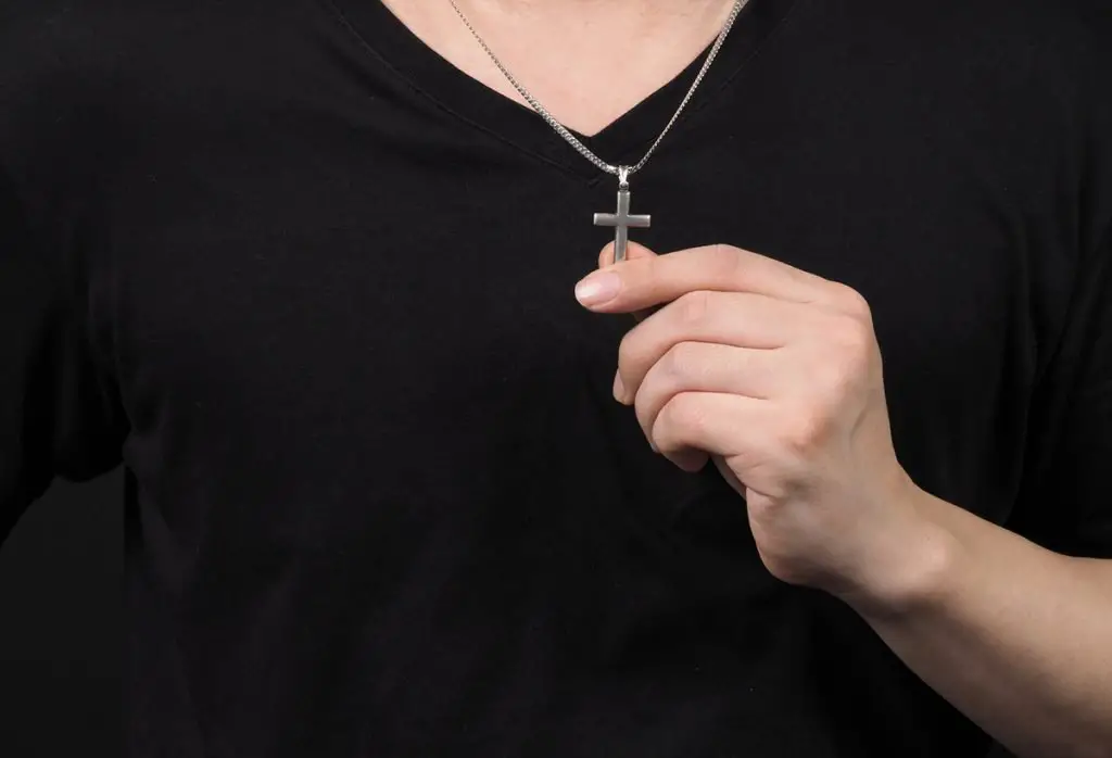 cross pendant made from silver and hold in man hand