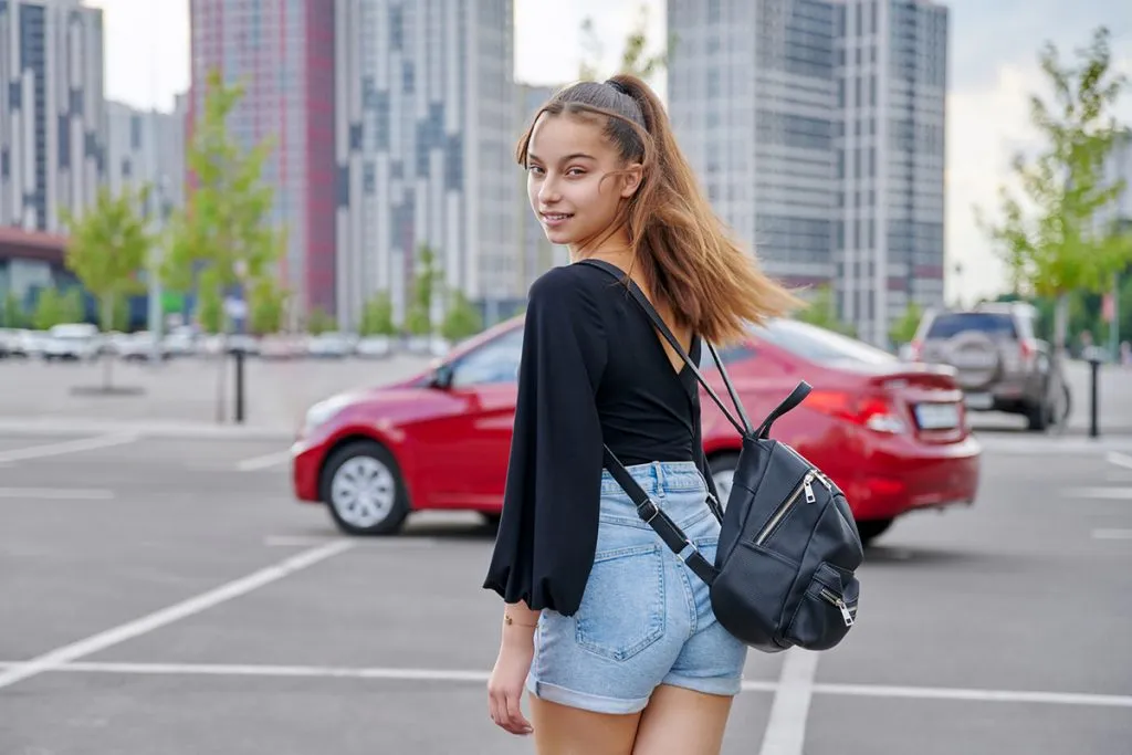 beautiful smiling teenage girl in shorts with backpack