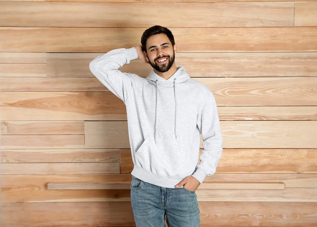a young man wearing a female hoodie at wooden wall