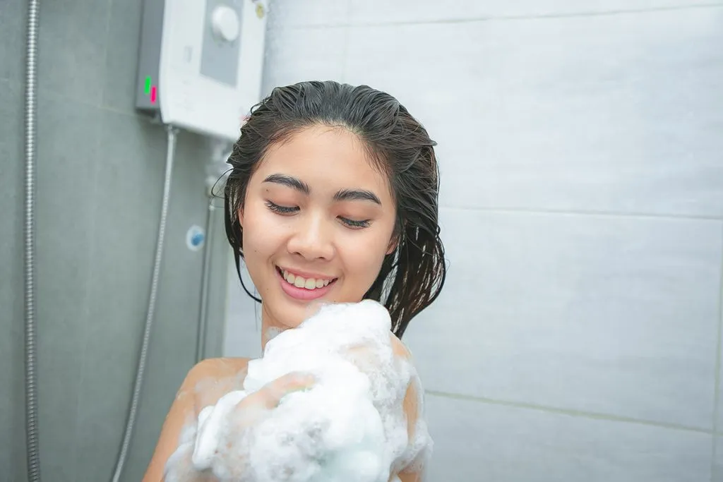 woman taking a shower enjoying foam on her shoulder