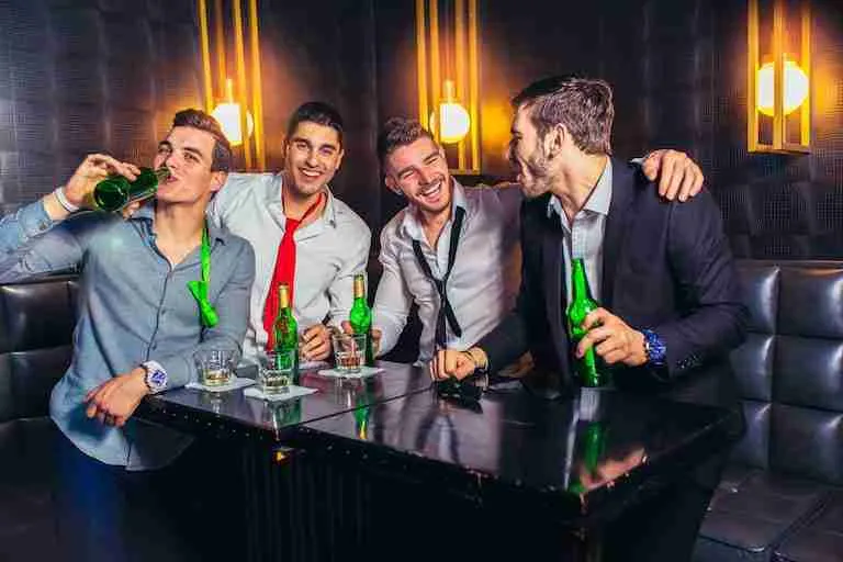 group of smiling male friends having fun in night club