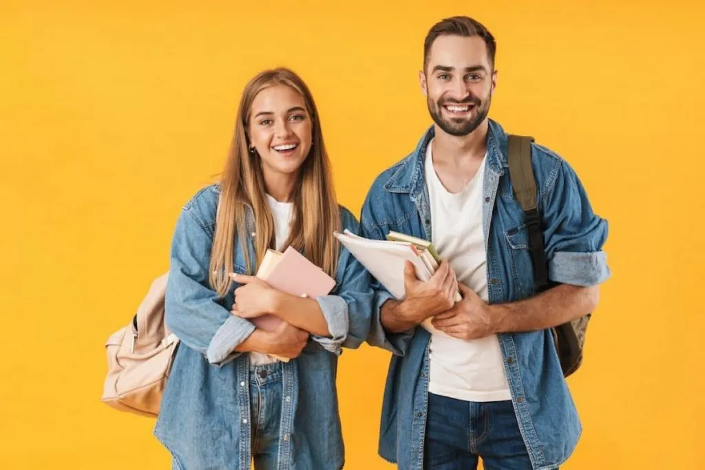 young students in denim clothes smiling while holding books