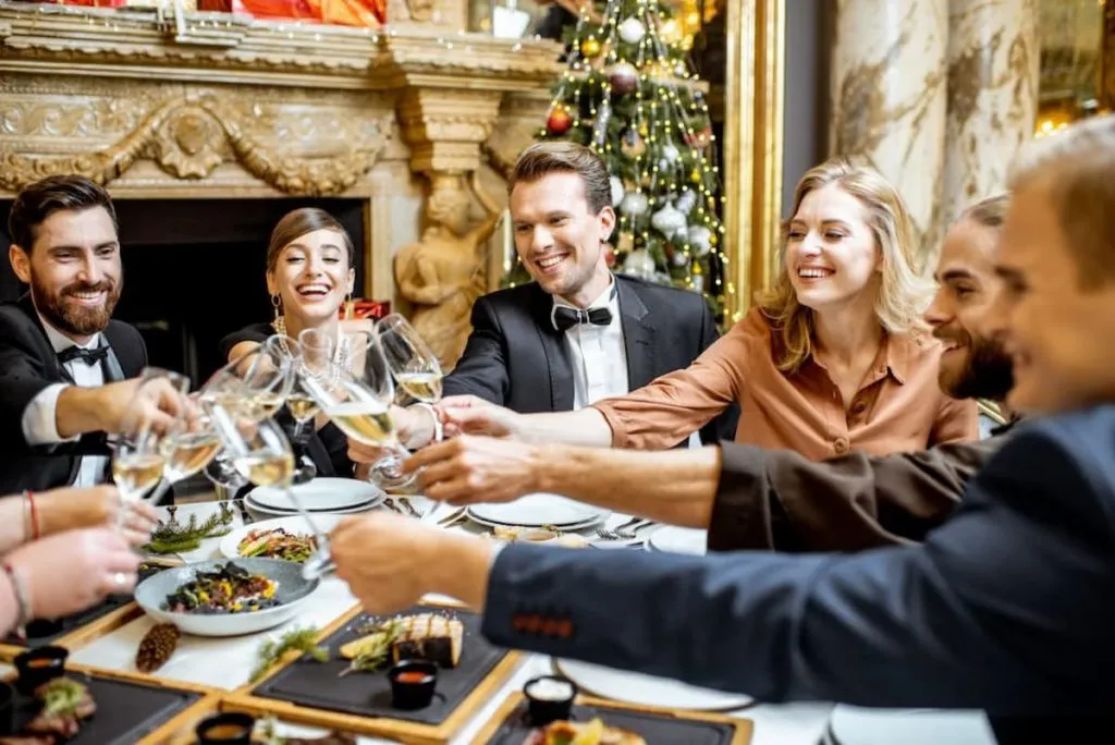 elegantly dressed group of people having fun, clinking wine glasses during a festive dinner