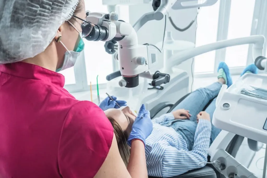 dentist examines the patient with a microscope in the dentist's office