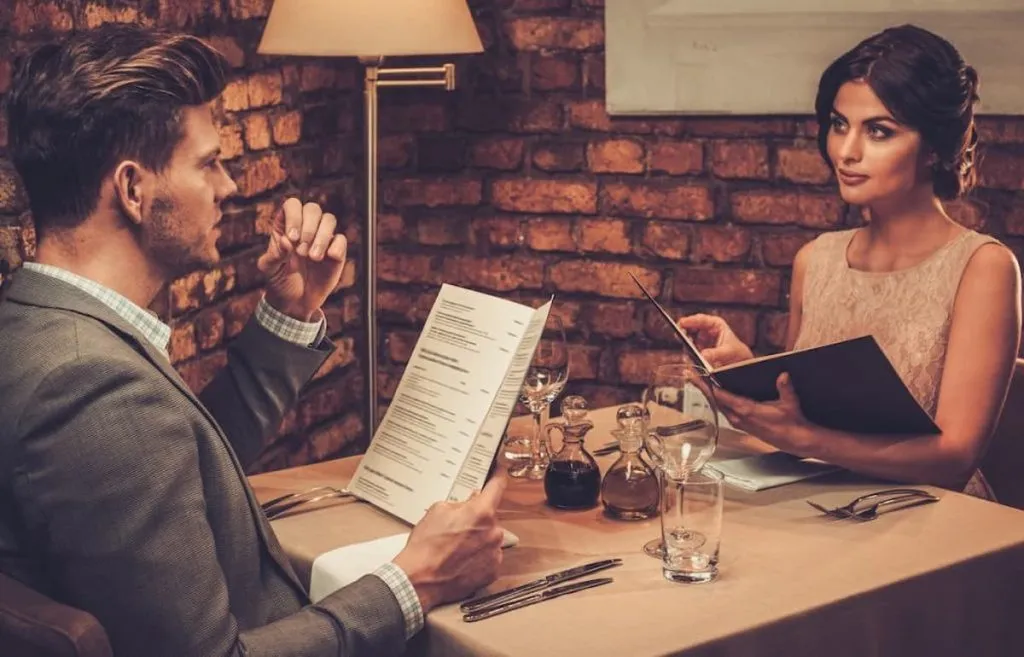 stylish wealthy couple with menu in a restaurant