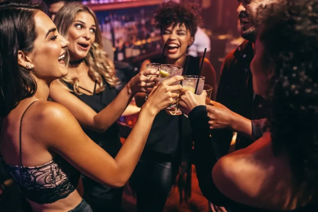 group of friends partying in a nightclub and toasting drinks