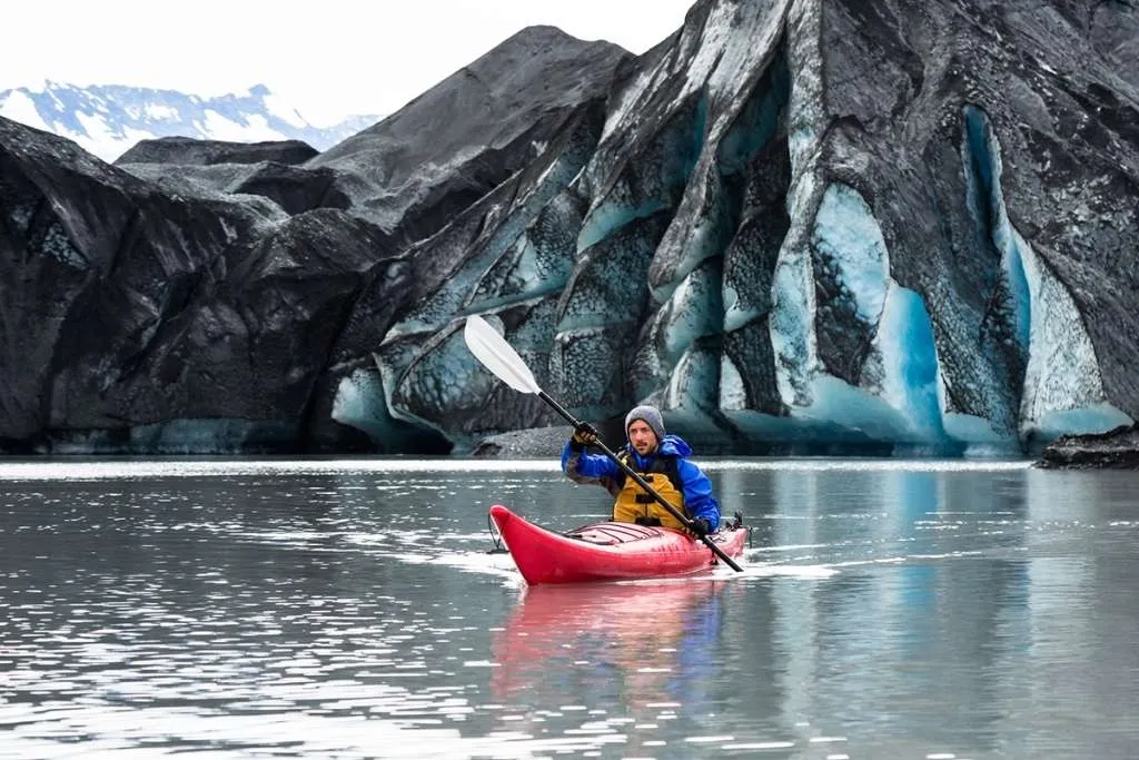 A man paddles his kayak away from the terminus of the Spencer Glacier