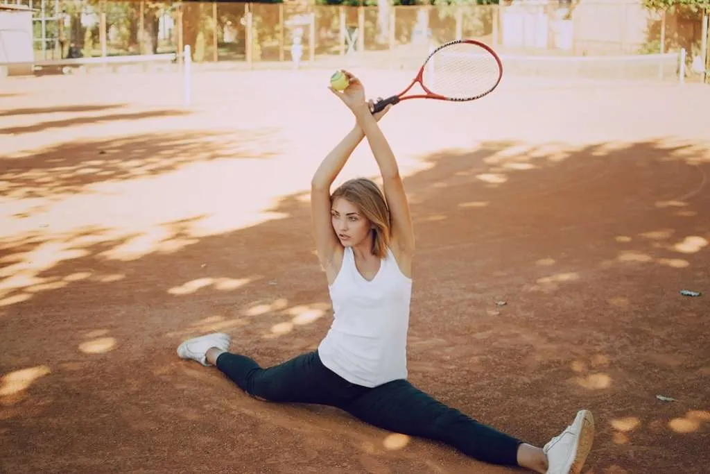 girl in leggings in a park on the tennis grounds holds a tennis racket