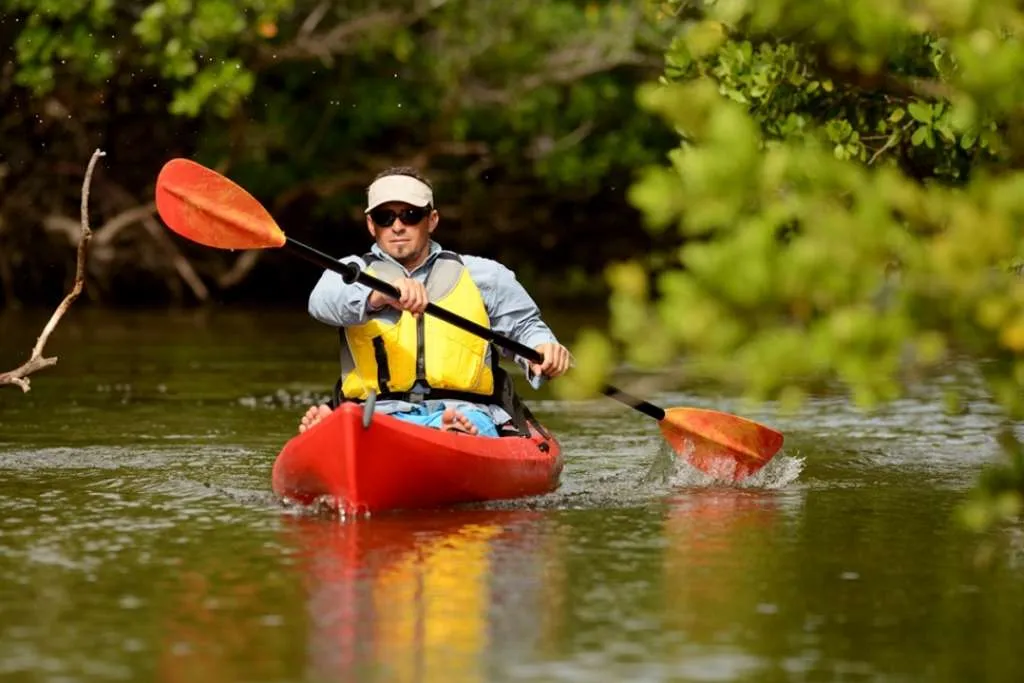 man paddling in a red kayak in Florida