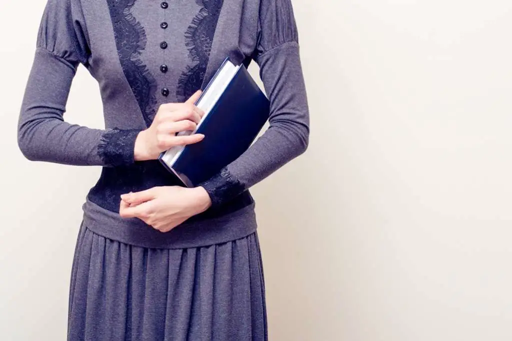 woman in gray vintage dress holding bible