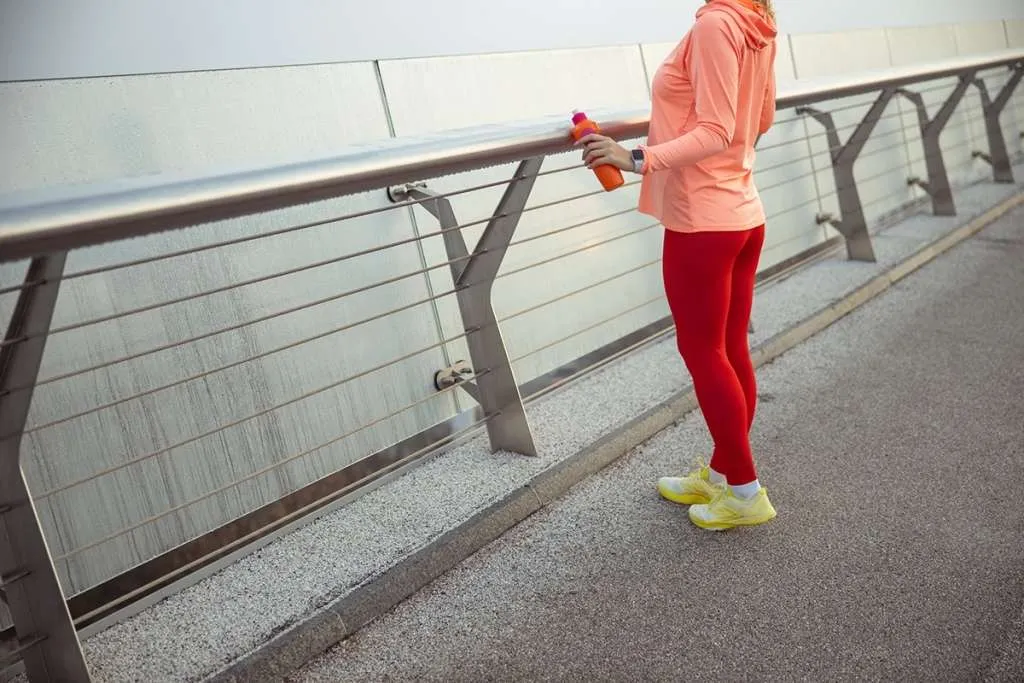 woman in sports leggings holds a bottle of water